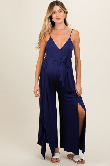 woman wearing a navy blue maternity jumpsuit with a deep v-neck and side slits, showcasing her baby bump