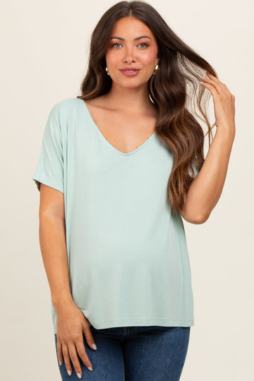 woman wearing a light green short sleeve maternity top with a v-neck and a relaxed fit