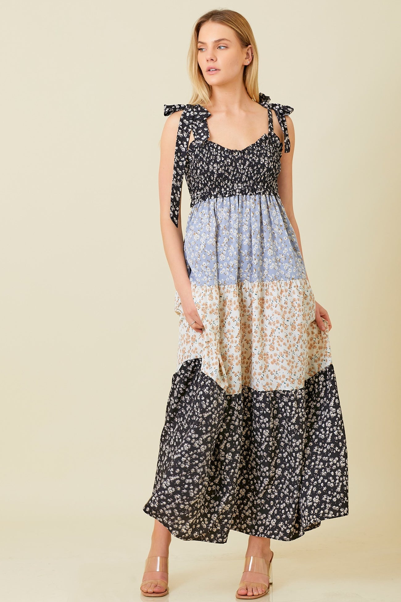 woman wearing a floral maxi dress with tie straps in black, blue, and cream colors
