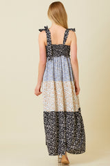 woman wearing a multi-patterned sleeveless maxi dress with tie shoulder straps and a smocked bodice, viewed from behind