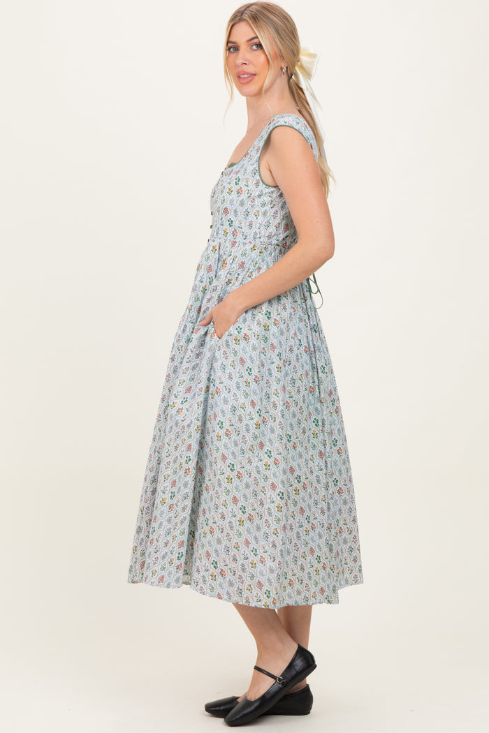 woman wearing a sleeveless light blue floral midi dress with pockets and a fitted bodice