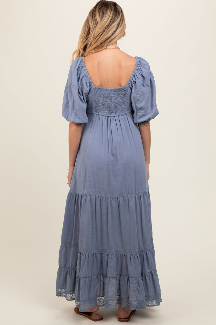 woman wearing a blue maternity maxi dress with puff sleeves and tiered ruffles, showcasing a baby bump from the back