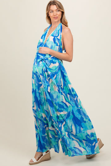 woman wearing a blue and green patterned maternity maxi dress with a halter neck and a visible baby bump