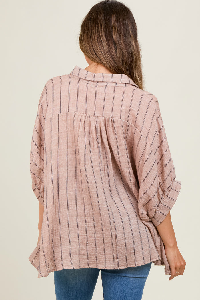 woman wearing a blush striped maternity top with rolled sleeves, showing her back and a flowing fit over her baby bump