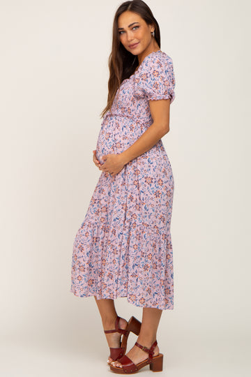 Pregnant woman in a lavender floral smocked maternity midi dress with puff sleeves and brown platform sandals