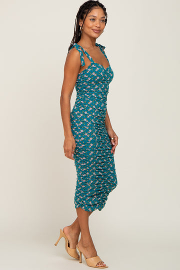 woman wearing a teal floral midi dress with tie straps and a form-fitting silhouette