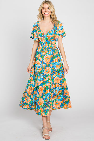 woman wearing a vibrant floral maxi dress with short flutter sleeves and a cinched waist
