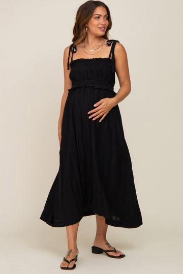 pregnant woman wearing a black smocked maternity midi dress with tie straps and sandals