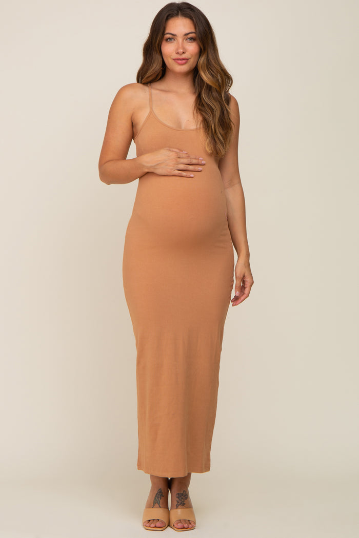 woman wearing a tan ribbed maternity maxi dress and cradling her baby bump