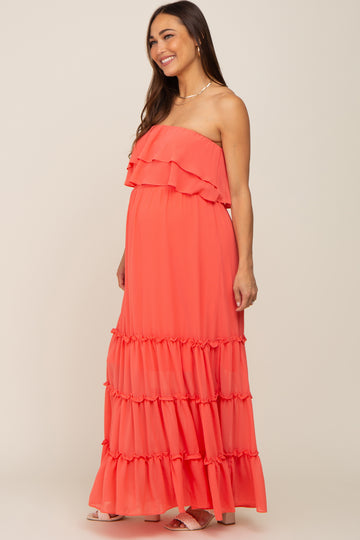 woman wearing a coral strapless tiered maternity maxi dress with ruffle details