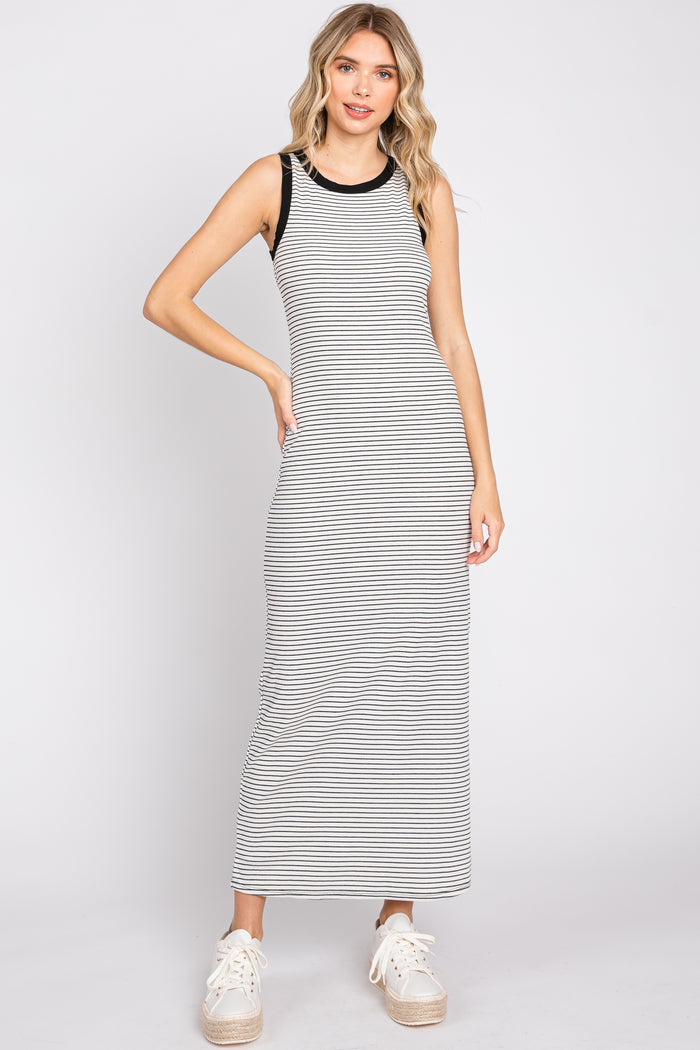 woman wearing a sleeveless black and white striped maxi dress with white platform sneakers