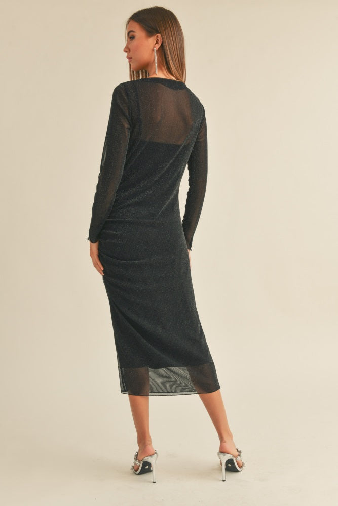 woman wearing a black long sleeve mesh midi dress with a fitted silhouette and a sheer back detail
